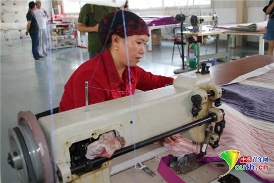 大斌家纺员工李玲正在用缝纫机机加工褥子.蔺洁丽 摄