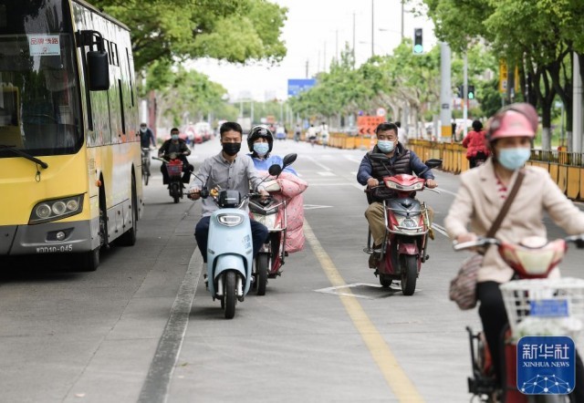在上海市嘉定区新成路街道，人们骑行在道路上（5月9日摄）。