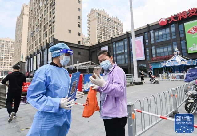 在上海市嘉定区一家超市，工作人员在商超入口处核验购物者的防疫码（5月9日摄）。