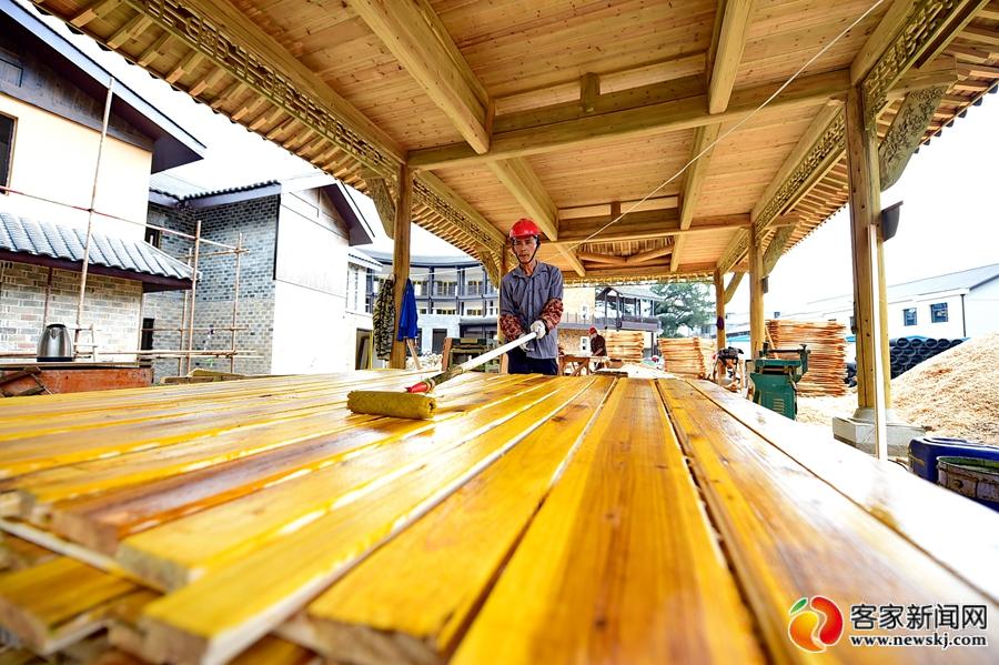 木匠工人在给古建筑修缮所需的瓦梁木材刷防腐桐油.
