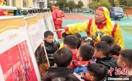 图为江西抚州市崇仁县非遗表演者正在给孩子们介绍相山板凳龙。(资料图)崇仁县融媒体中心供图